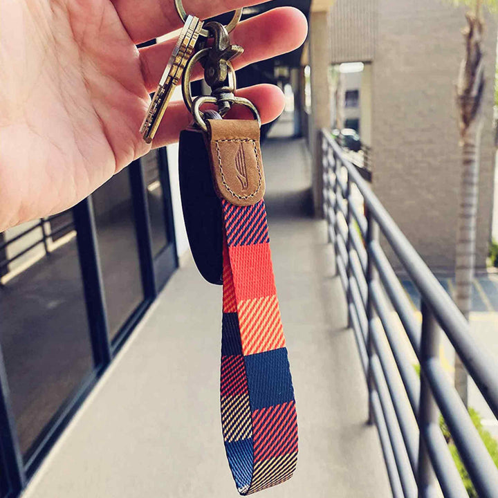 People holding orange yellow navy multicolor hand wrist lanyard with keys on the hand