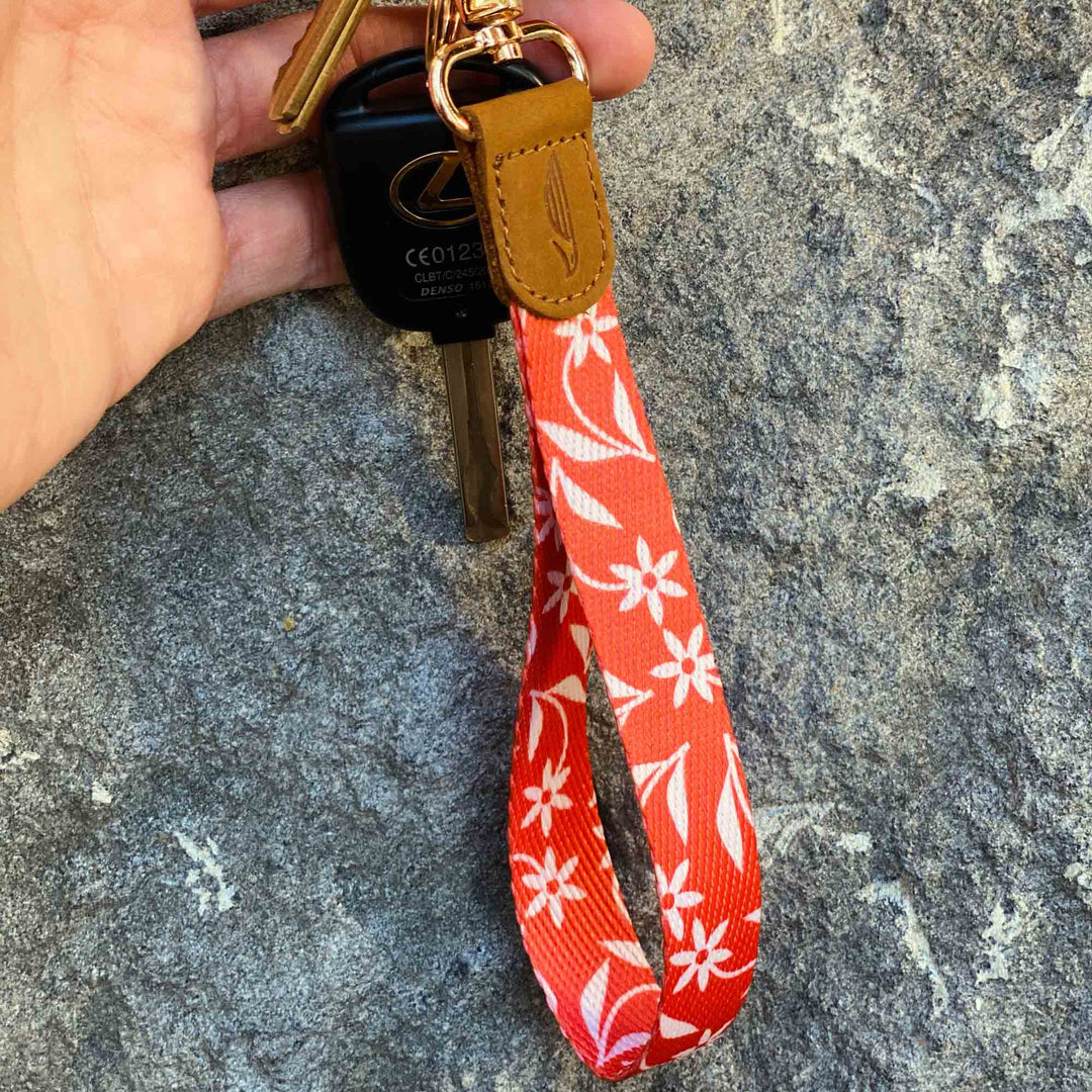 Orange creme color floral patterned hand wrist lanyard with keys on the hand stone background