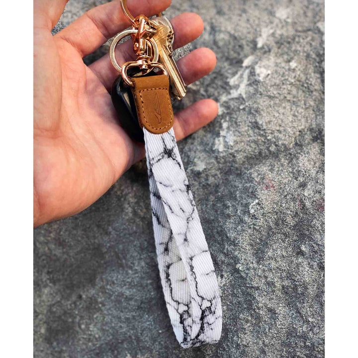 White black marble patterned hand wrist lanyard with keys on the hand stone background