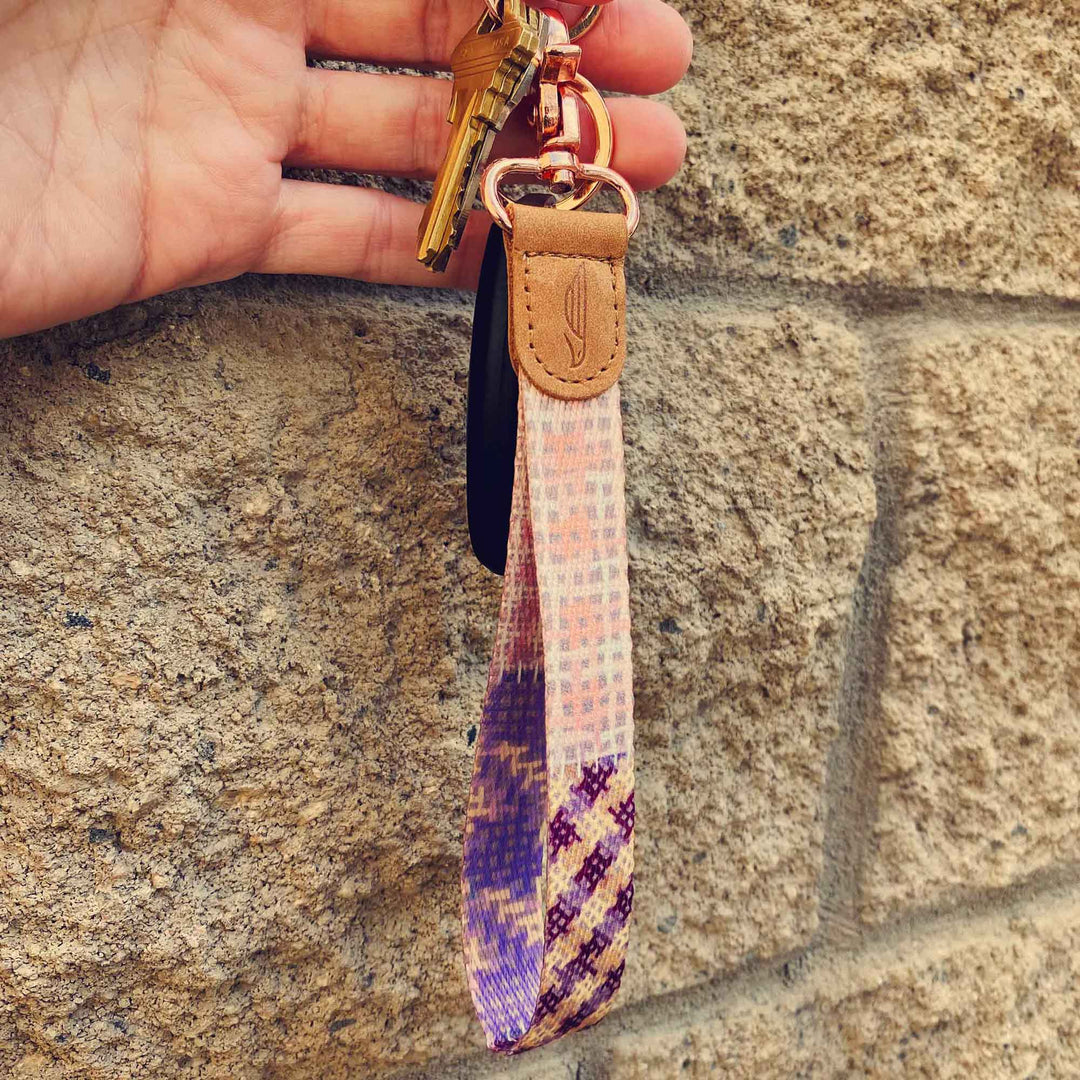 People holding pink violet purple multicolor hand wrist lanyard with keys on the hand