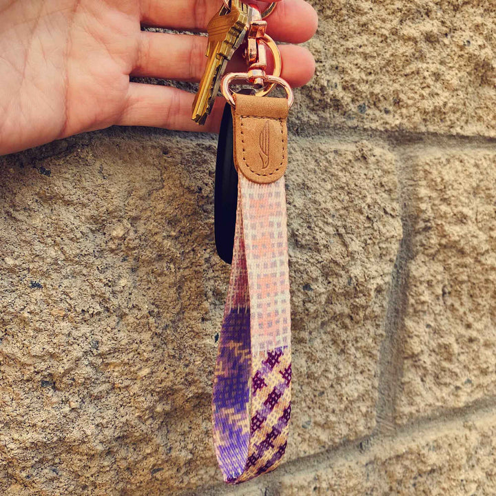 People holding pink violet purple multicolor hand wrist lanyard with keys on the hand