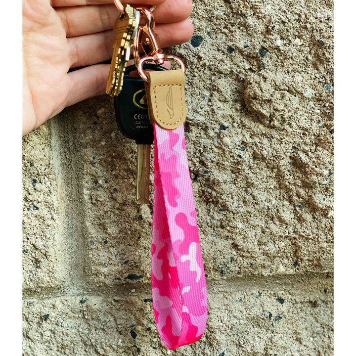 camouflage patterned pink hand wrist lanyard keychain with keys on the hand stone wall background