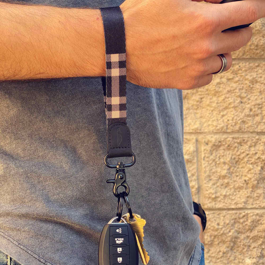 Man wears black and cream cool wrist lanyard to carrying keys