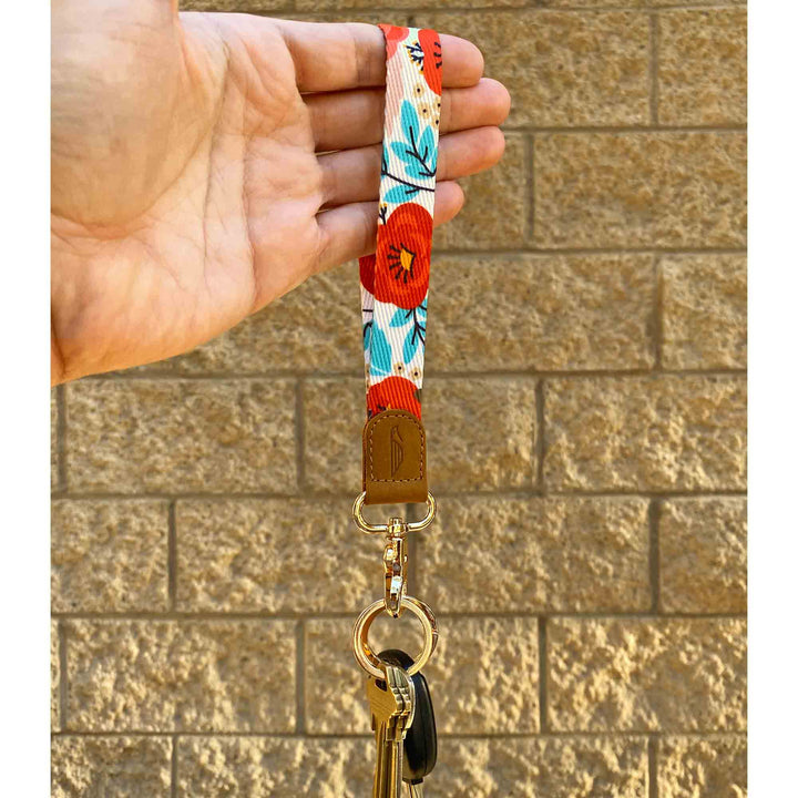 Red blue poppy floral patterned hand wrist lanyard with keys on the hand stone wall background