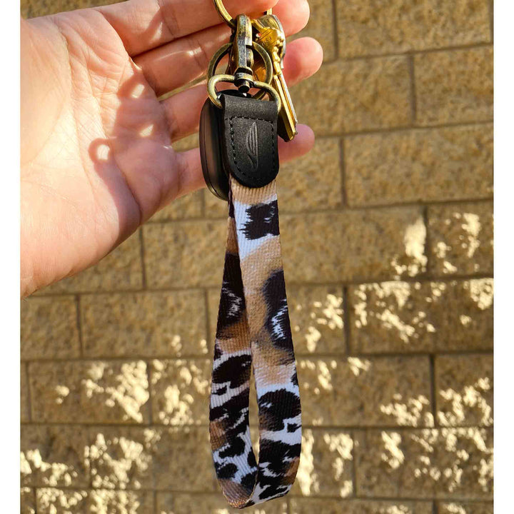 black brown white leopard patterned hand wrist lanyard with keys on the hand stone wall background